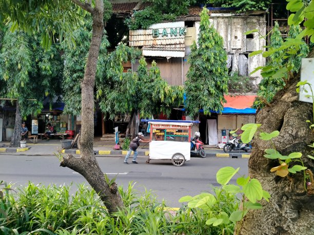 在这条高速公路上，有人们推着手推车的背景是一幢凌乱的银行大楼图片下载