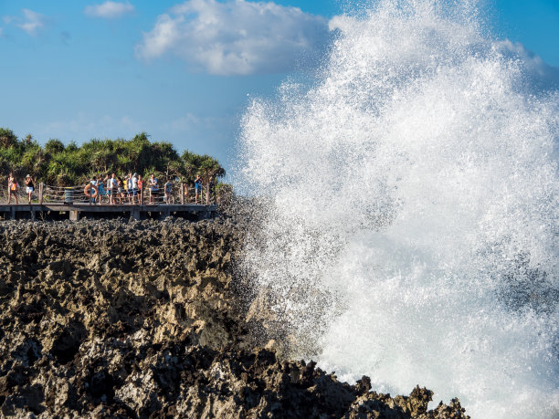 游客们在巴厘岛拍摄海浪撞击礁石的照片图片下载