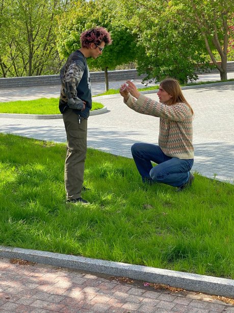 年轻的白人男性在城市公园拍下了他紫色头发的朋友的照片。图片下载