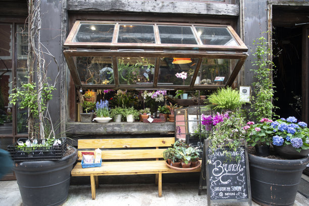 植物和鲜花生长在餐厅或咖啡馆。入口带有长凳的复古外观图片下载