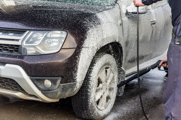 一个男人在洗车。一个男人在洗车。洗车场的一辆泡沫雷诺。图片下载
