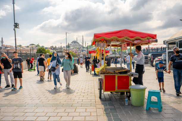 伊斯坦布尔夏天的大街上，一名男子在推车上卖烤玉米。土耳其街头小吃生意图片下载