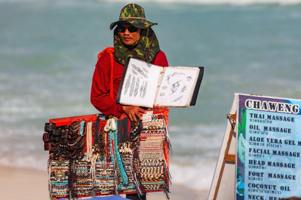 泰国苏梅岛——2011年1月9日:在苏梅岛的查翁海滩上，泰国的珠子和手镯销售商向游客展示纹身样品图片下载