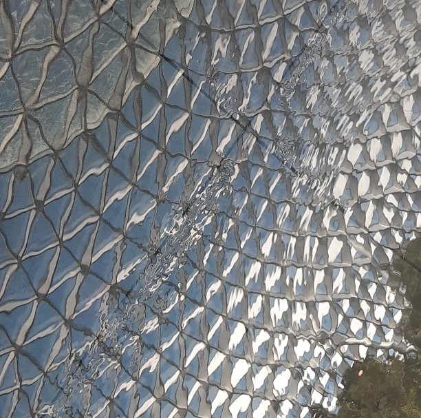 瀑布从钢质玻璃屋顶流淌而下，倒映在水中图片下载