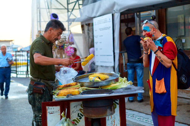 一个街头小贩在城市的街道上炸薯条和卖玉米。那家伙在街上吃玉米图片下载