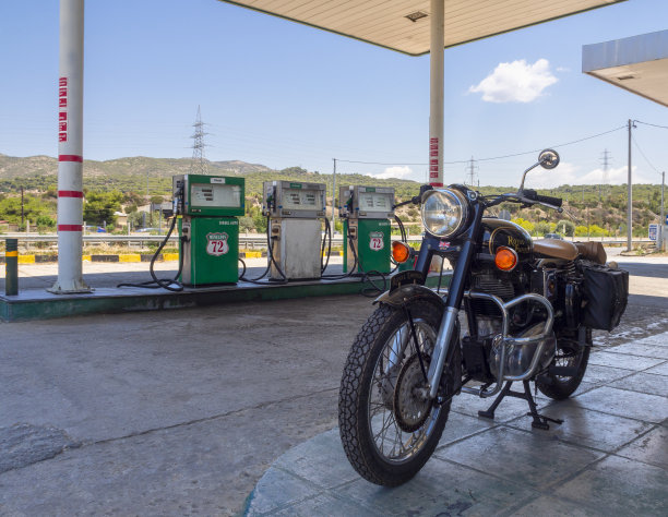 复古摩托车皇家恩菲尔德站在加油站在雅典-帕特拉斯高速公路在希腊图片下载