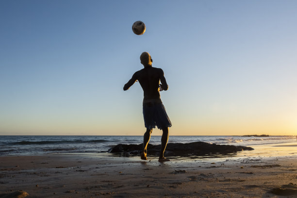 一名技术娴熟的年轻人在昂蒂纳海滩的日落时分踢沙滩足球图片下载