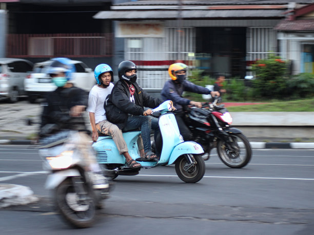 在印度尼西亚万隆的巴斯德地区，两个人骑着摩托车下午经过一个十字路口的长曝光照片图片下载