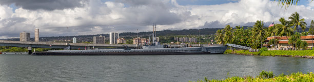 鲍芬号潜艇的全景照片，停靠在珍珠港的亚利桑那号纪念游客中心旁边。以檀香山和多云的天空为背景图片下载