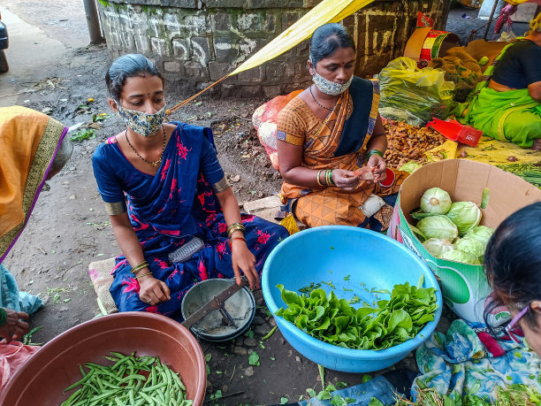 这张照片拍摄于印度马哈拉施特拉邦科尔哈布尔，照片中，两名年轻的印度妇女戴着口罩，在乡村蔬菜市场出售新鲜的有机蔬菜图片下载