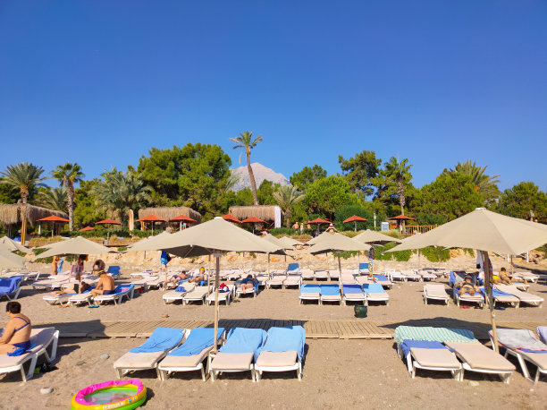 沙滩上的躺椅上有伞，躺椅上有山图片下载