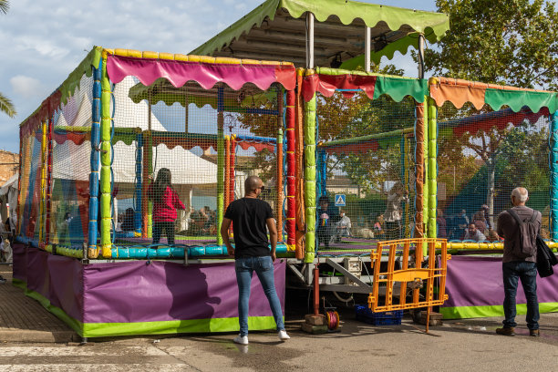 10月31日，一年一度的秋季集市在马略卡镇波雷雷斯举行。孩子们在蹦床上玩耍，他们的父母看着他们。新常态图片下载