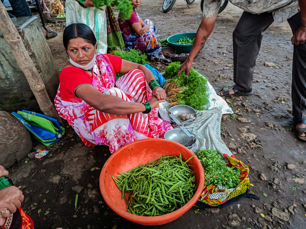 这张照片拍摄于印度马哈拉施特拉邦科尔哈布尔，照片中年轻的印度妇女戴着口罩，在乡村蔬菜市场出售新鲜的有机蔬菜图片下载