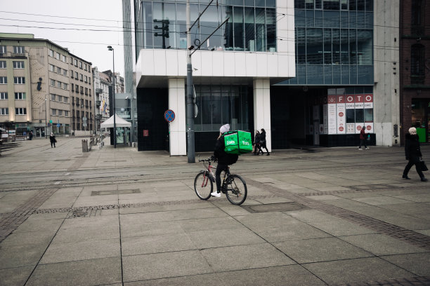 司机骑自行车为快速餐厅送货。外卖食品快递袋。优步用滑板车送餐。图片下载