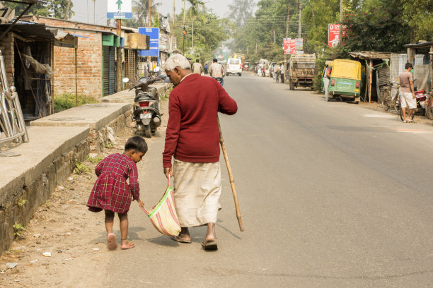 一个小女孩试图帮助一个老人拿他的包。有选择性的重点。图片下载