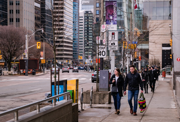 加拿大安大略省多伦多市中心，行人走在大学大道的人行道上，背景是汽车和高层建筑图片下载