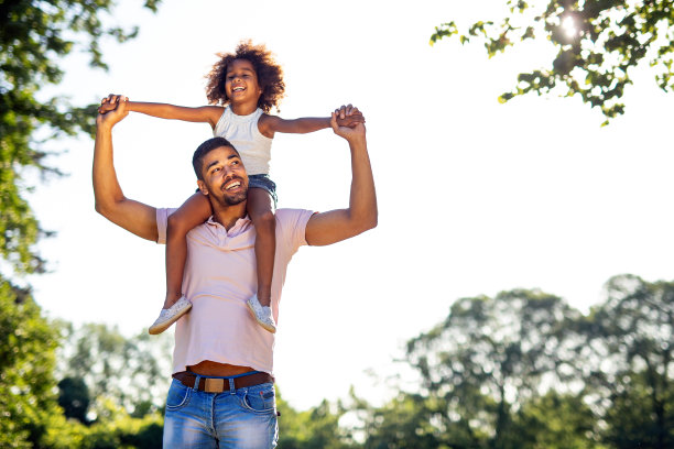 快乐的黑人父亲背着女儿在户外的肖像。家庭幸福爱的理念。图片下载