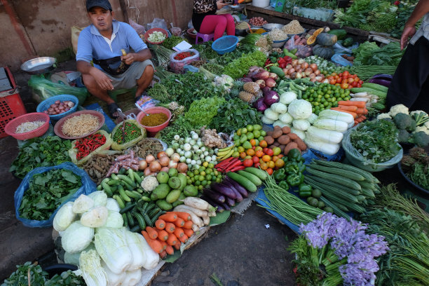 一名男子在柬埔寨马德望的普萨尔纳特街市场卖新鲜蔬菜图片下载