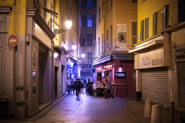 在法国老Vieux Nice市中心，一名骑着自行车的外卖员在深夜将食物送到路边的咖啡馆。图片下载