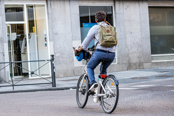 BiciMad自行车租赁服务的用户，在一个城市的十字路口骑着他的一辆自行车转弯。图片下载