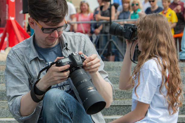 摄影师正在现场拍摄。一男一女。一个人检查照片，另一个人拍照。图片下载
