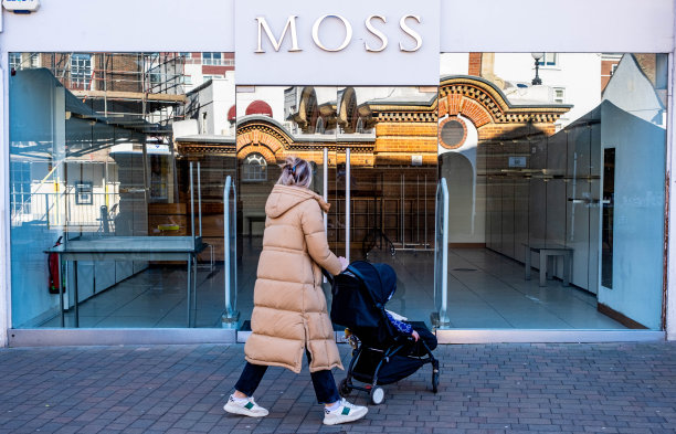 一位推着婴儿车的妇女走过一个关闭的空无一人的商业街图片下载