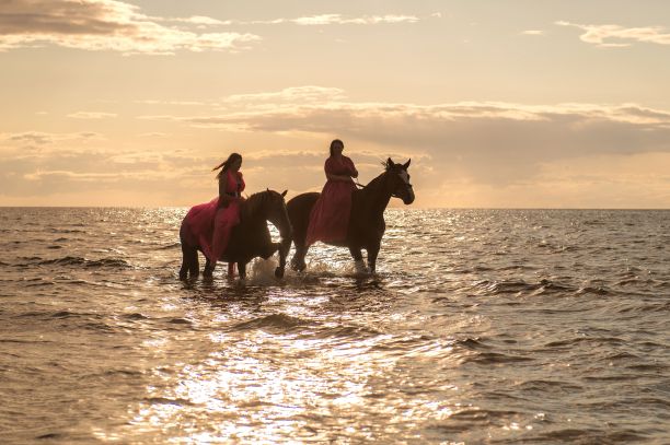 美丽的照片，两个女人在日落的海滩上骑马图片下载