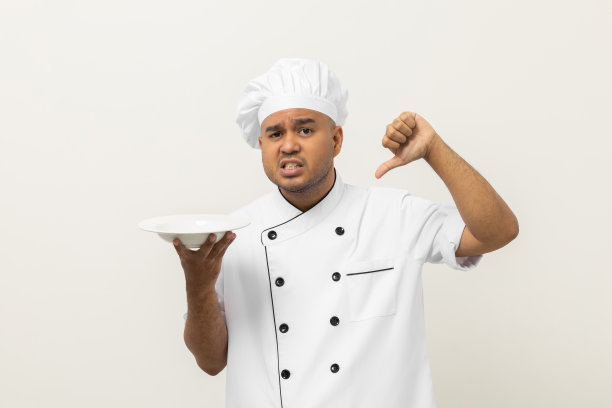 难闻的气味和不好吃的食物。年轻的亚洲大厨手里拿着的菜已经腐烂了，菜的味道又臭又恶心。肮脏的食物和背景孤立的厨师。图片下载