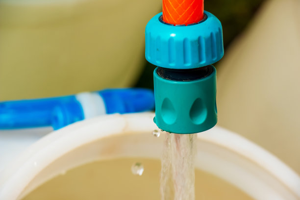 一根软管喷出的水充满了一个塑料桶。的背景图片。世界饮用水危机的概念。图片下载