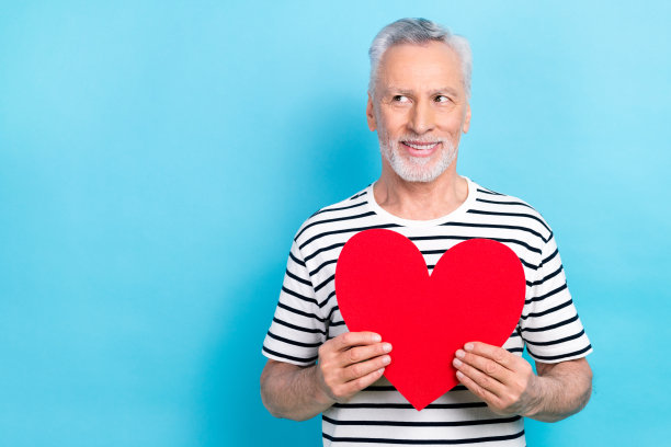 照片正面时髦的男人穿着时髦的衣服，手拿红纸卡，仰望空旷的空间，提供孤立的蓝色背景图片下载