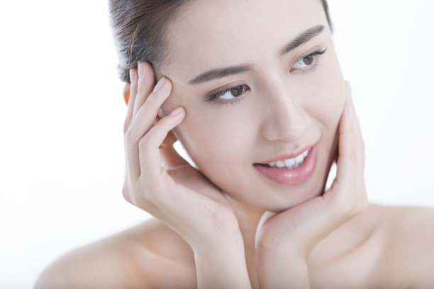 在白色背景照片上，年轻的女士在涂抹了血清后抚摸着她光滑的皮肤图片下载