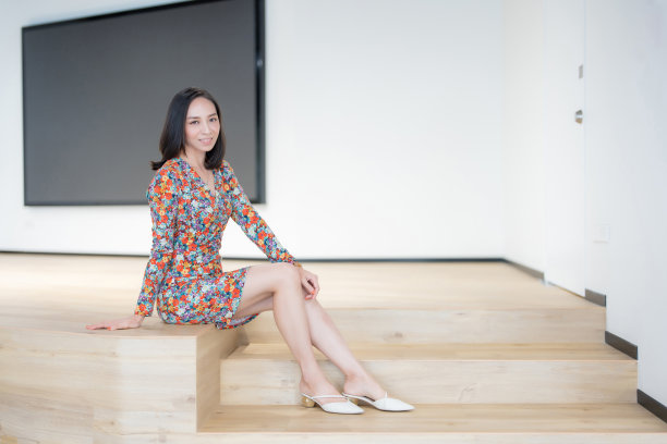 亚洲女性高管，短发公司负责人，穿碎花套装，在办公室里坐着摆姿势拍漂亮的照片，微笑，眼神交流，后面有一个大显示器。图片下载