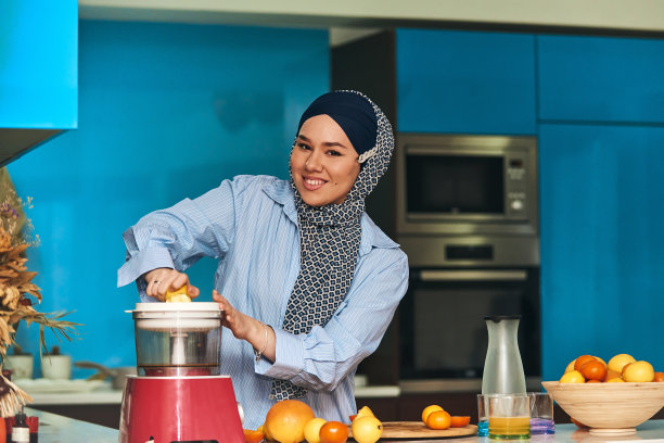 阿拉伯妇女在现代厨房里做果汁。家的概念。健康的生活方式的概念。有选择性的重点。高质量的照片图片下载