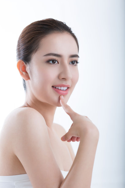 在白色背景照片上，年轻的女士用健美的皮肤抚摸她的下巴，感觉她的皮肤如丝般光滑图片下载