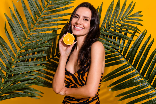 年轻开朗的女人持有橙色保湿纯清洁面部隔离在黄色背景的照片图片下载