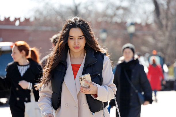 在城市街道上用智能手机行走的漂亮女人图片下载