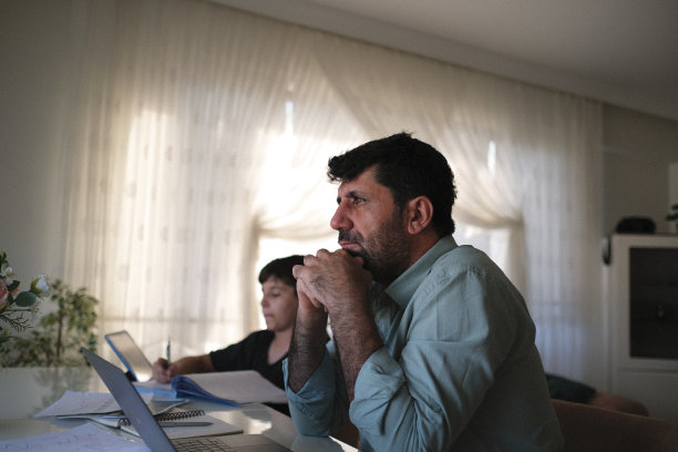 可爱的男孩正在学习电脑，爸爸在家里工作。在家教育的概念。库存图片图片下载