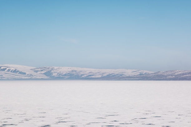 在卡尔斯冰冻的Cildir湖和雪山与冬天的蓝天景观图片下载