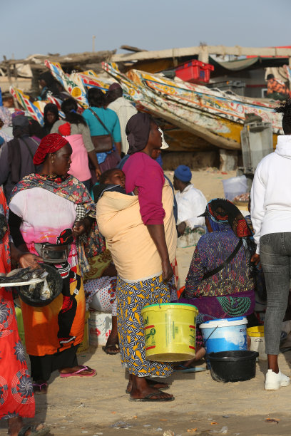 身穿传统民族服装的妇女，在非洲塞内加尔卡亚尔村。鱼市。母亲用吊带抱着婴儿图片下载
