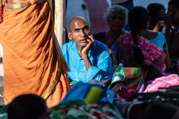 一个剃光头男子坐在拥挤的候车大厅里的偷拍照片图片下载