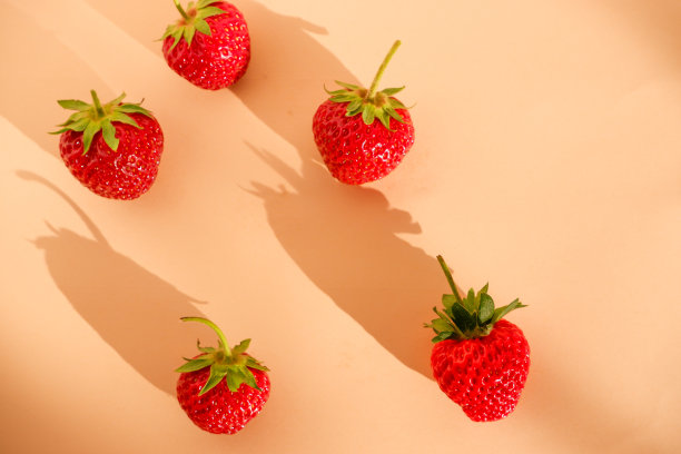 新鲜的浆果。鲜嫩多汁的红色草莓在柔和的粉色背景与阴影。特写照片。图片下载