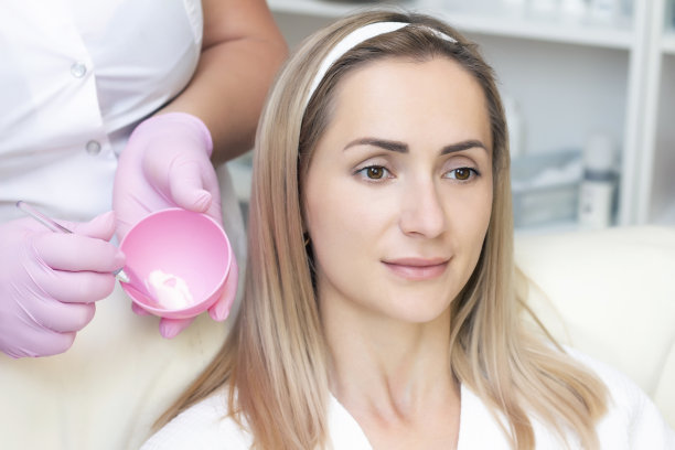 美容。可爱的年轻女子在美容院接受面部清洁手术的特写照片。图片下载