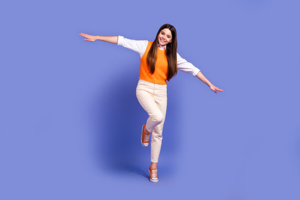 年轻的女学生的全身尺寸照片，青春期前的飞行手臂翅膀试图使平衡欣喜若狂，有乐趣孤立在紫罗兰色的背景图片下载