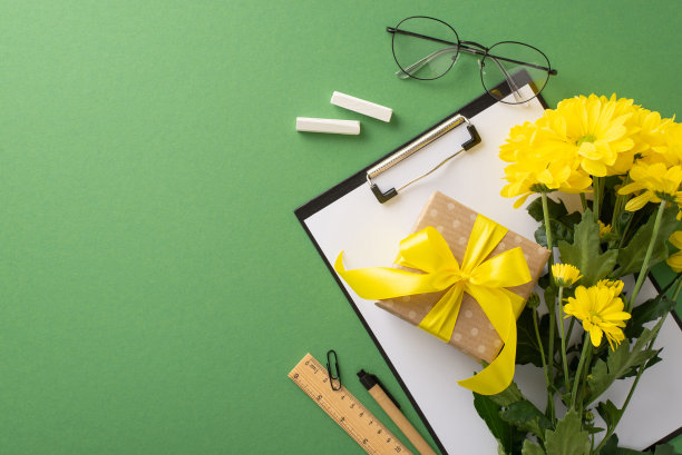 祝贺你的老师教师节的概念。剪贴板与学校用品，鲜花和礼品盒在黑板上孤立的背景与广告或文字的复制空间的俯视图照片图片下载