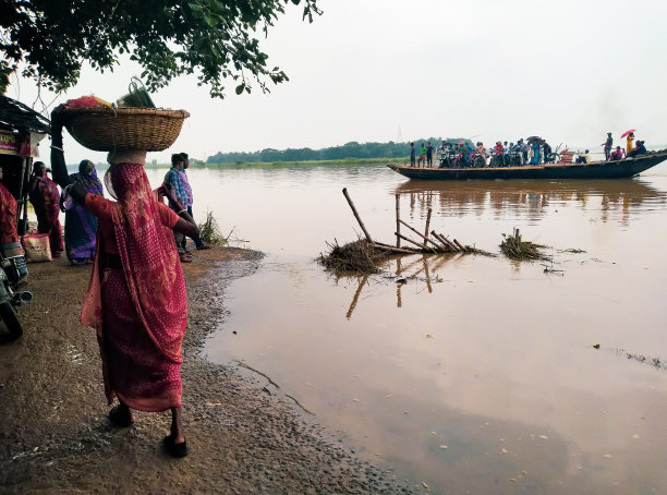 2021年，西孟加拉邦洪水泛滥——乡村被淹没，当地人乘坐木船过河图片下载