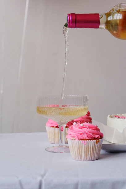 把不含酒精的白葡萄酒倒进漂亮的玻璃杯里。节日的照片，一个杯子的葡萄酒，松饼在一个白色的背景特写图片下载