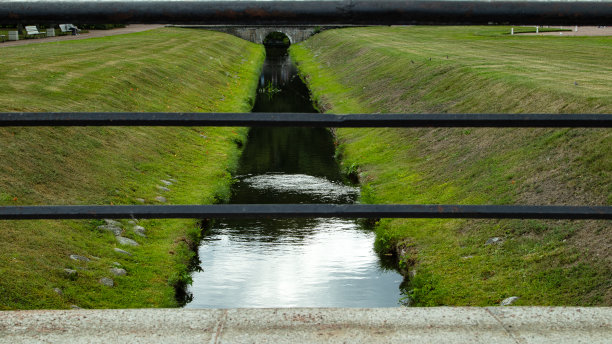 阳光明媚的日子里，河水穿过铁栅栏，图片下载