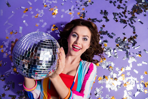 俯视图照片，兴奋的舞者女士躺在五彩纸屑地板上，闪闪发光的迪斯科球孤立的鲜艳的颜色背景图片下载