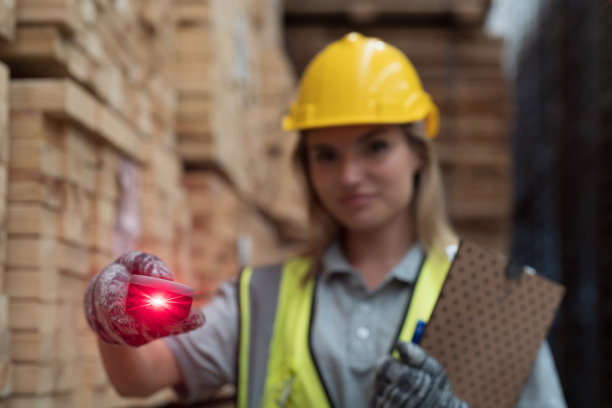 女仓库工人在木质仓库的木板堆上扫描条形码。在木材仓库仓库工作的女工图片下载