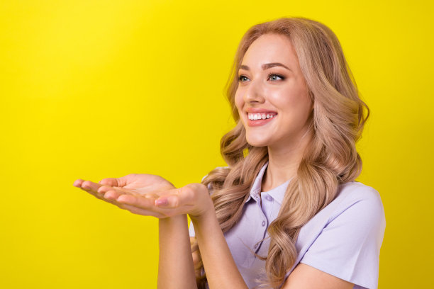 照片中可爱漂亮的女士穿着紫色马球抱着箱子看着抱着胳膊空空荡荡的黄色背景图片下载